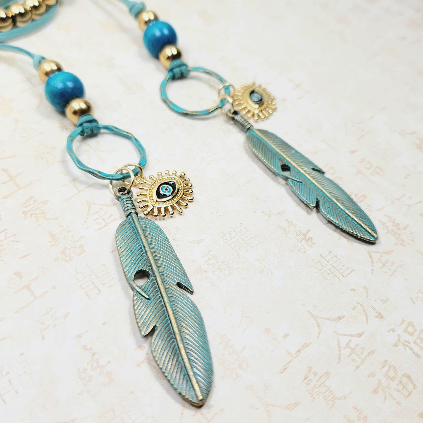 Boho Evil Eye Feather Necklace – Handmade Jewelry with Brass Feathers, Teal Wood Beads, Golden Accents & Faux Suede Cord